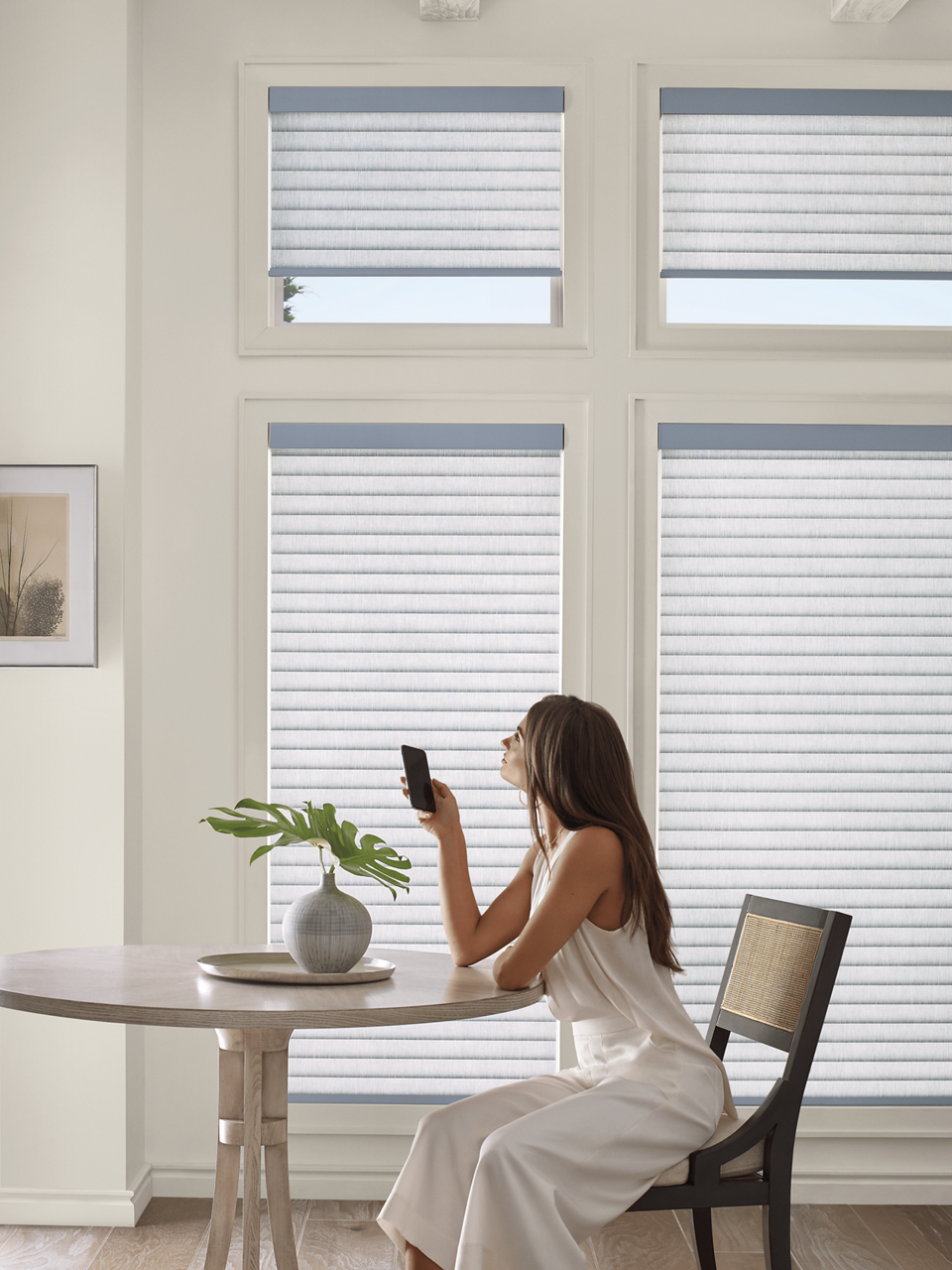 Woman operating her motorized blinds in a naturally lit dining room.